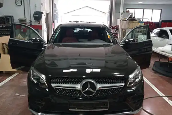 Talleres de chapa y pintura en Valencia con coche Mercedes negro en reparación dentro del taller