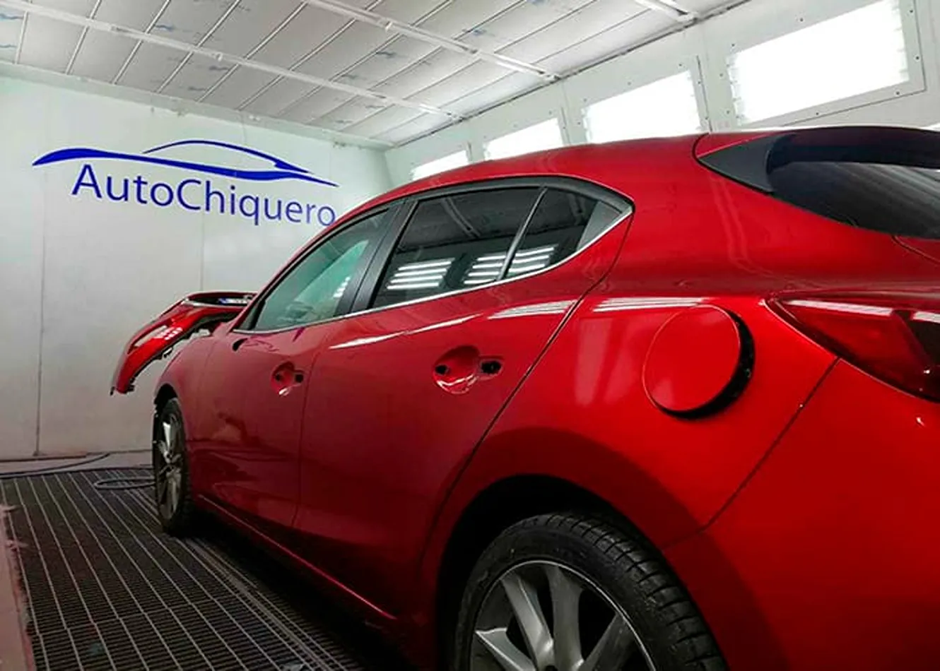 Coche rojo dentro de la cabina de pintura de Talleres Aparicio