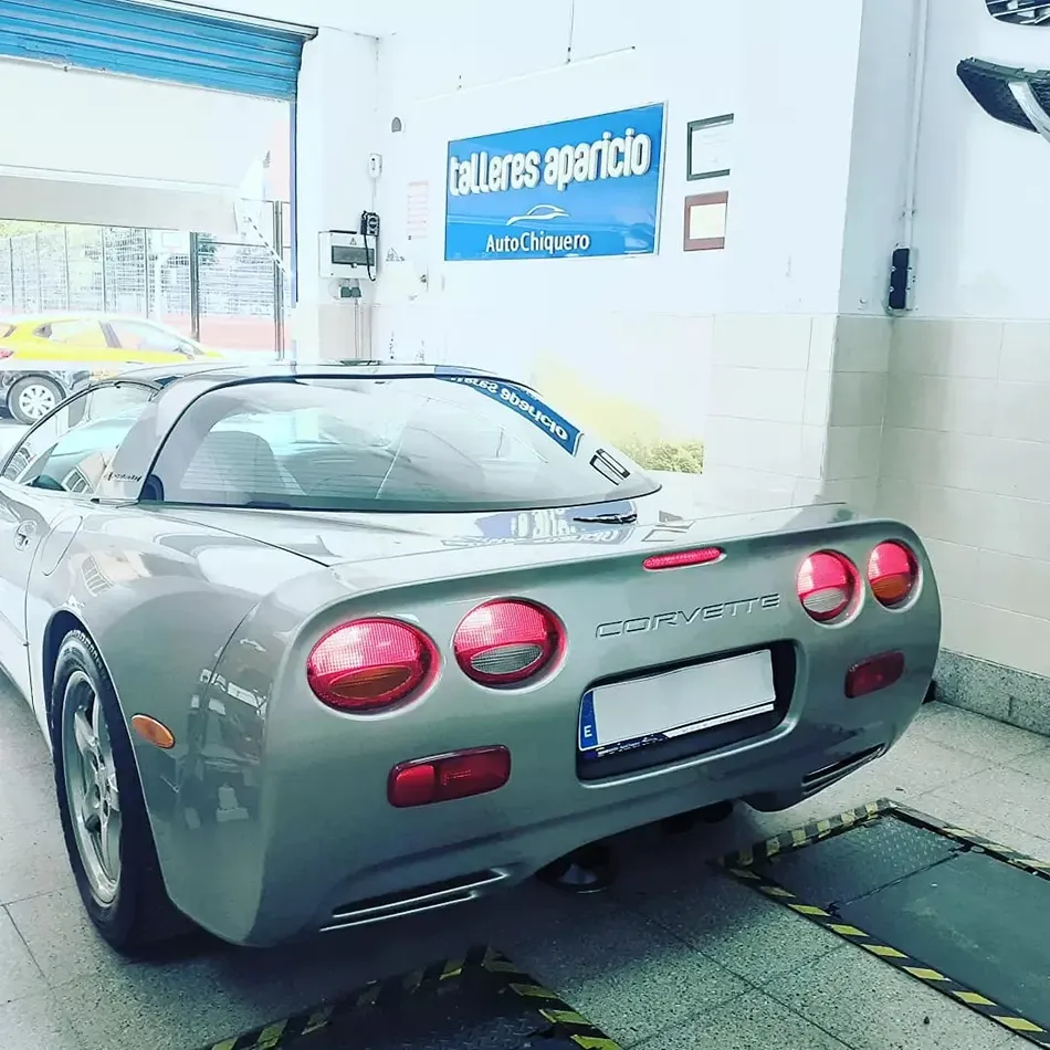 Corvette gris dentro de taller especializado de carrocería